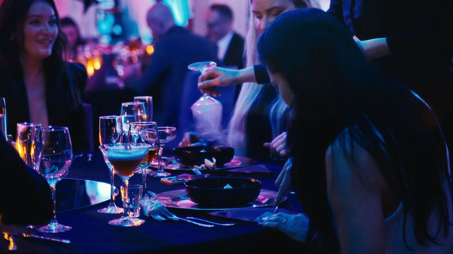 Goście przy nakrytym stole podczas kolacji w fioletowym świetle