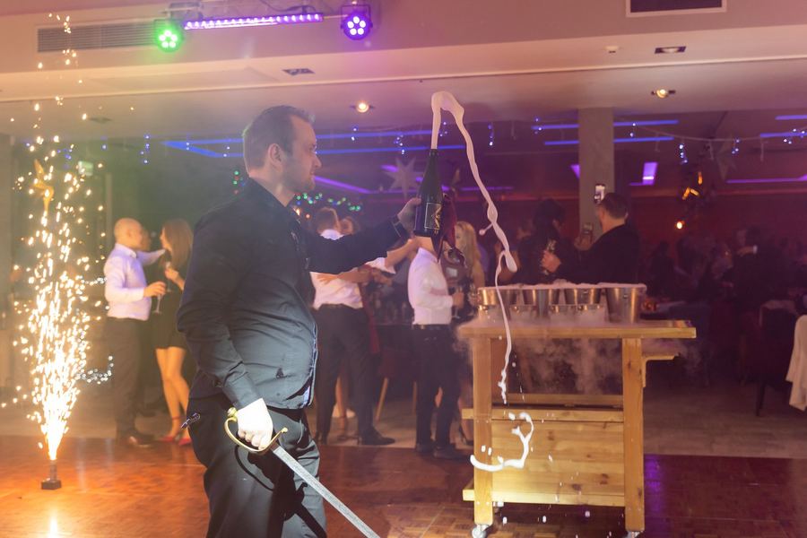 Otwieranie szampana szablą przy zimnych ogniach na sali