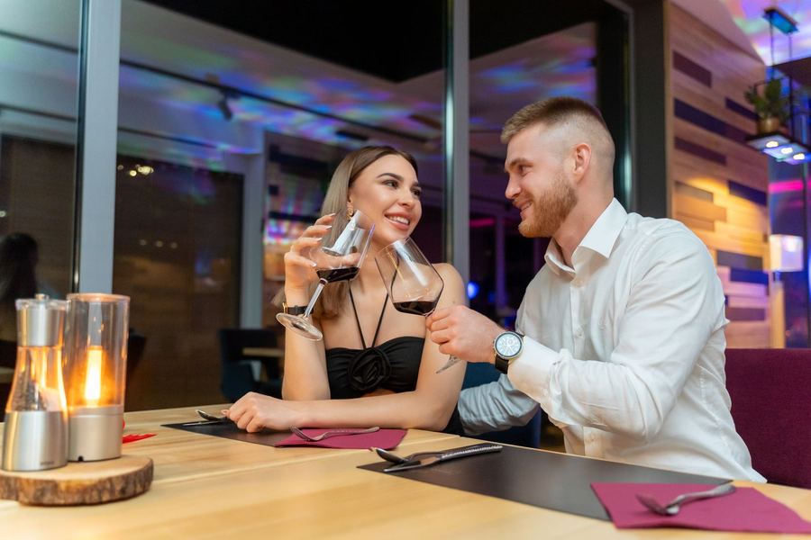 Para wznosi toast winem przy stoliku ze świecami