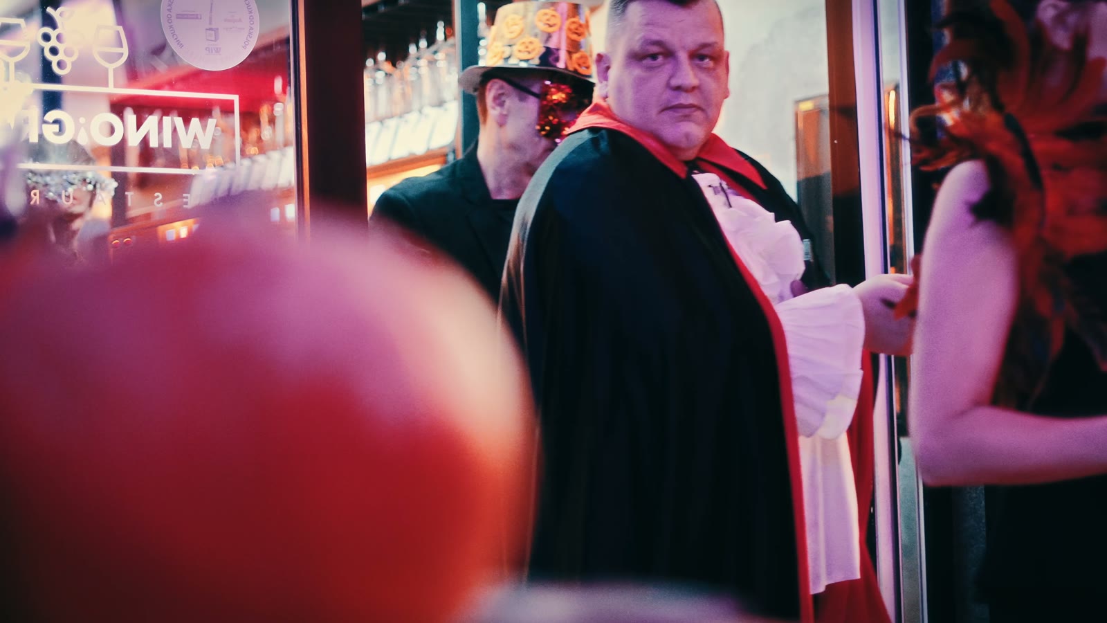 Goście w przebraniach wampira i masce z piór przy wejściu, Halloween 2025