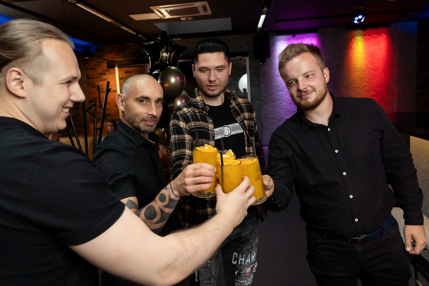 Czterech mężczyzn wznosi toast pomarańczowymi drinkami
