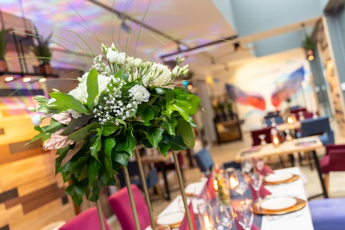Bukiet białych kwiatów z zielenią na tle sali restauracyjnej