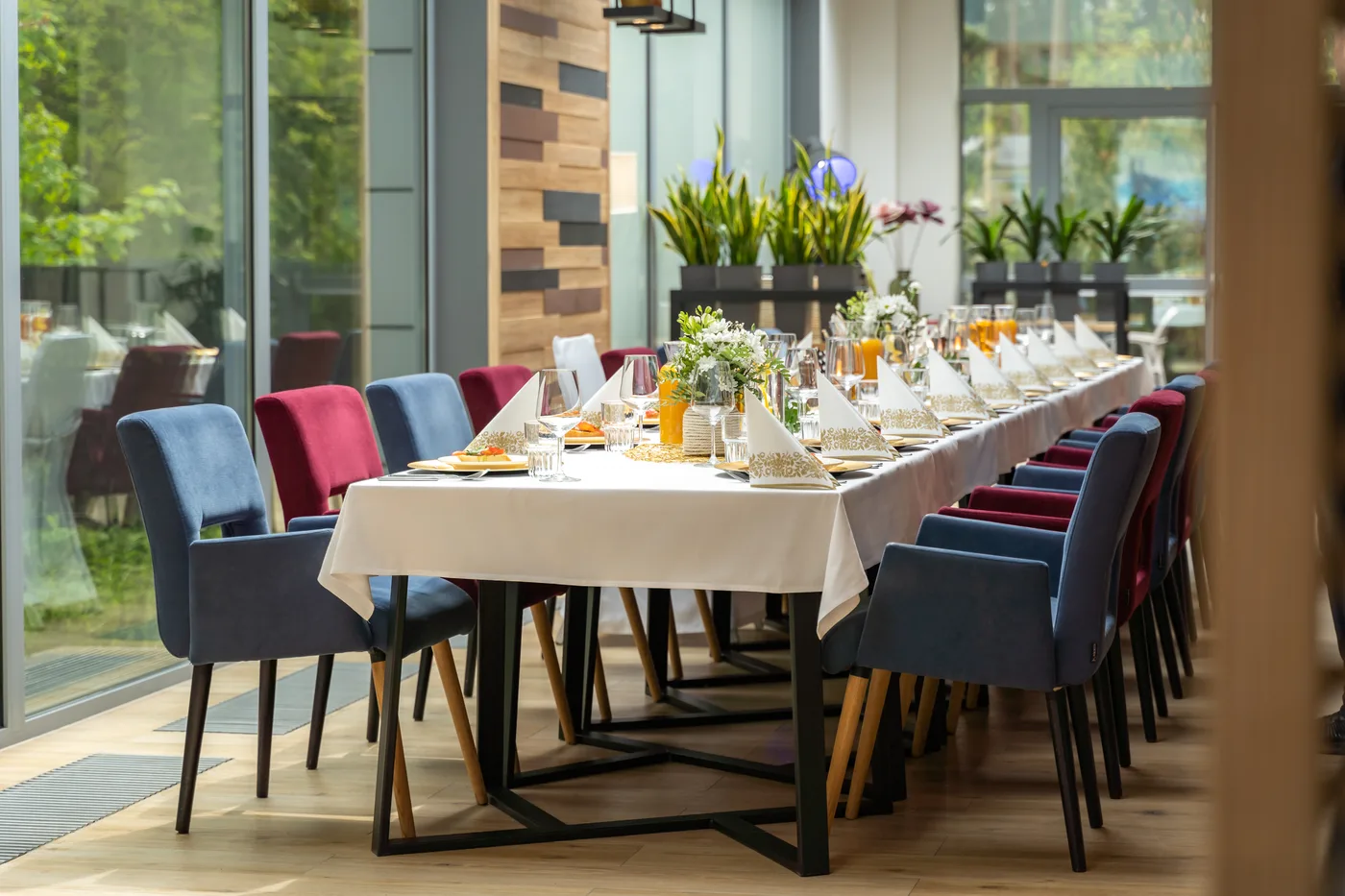 Jasna sala restauracyjna z długim stołem bankietowym przy panoramicznych oknach