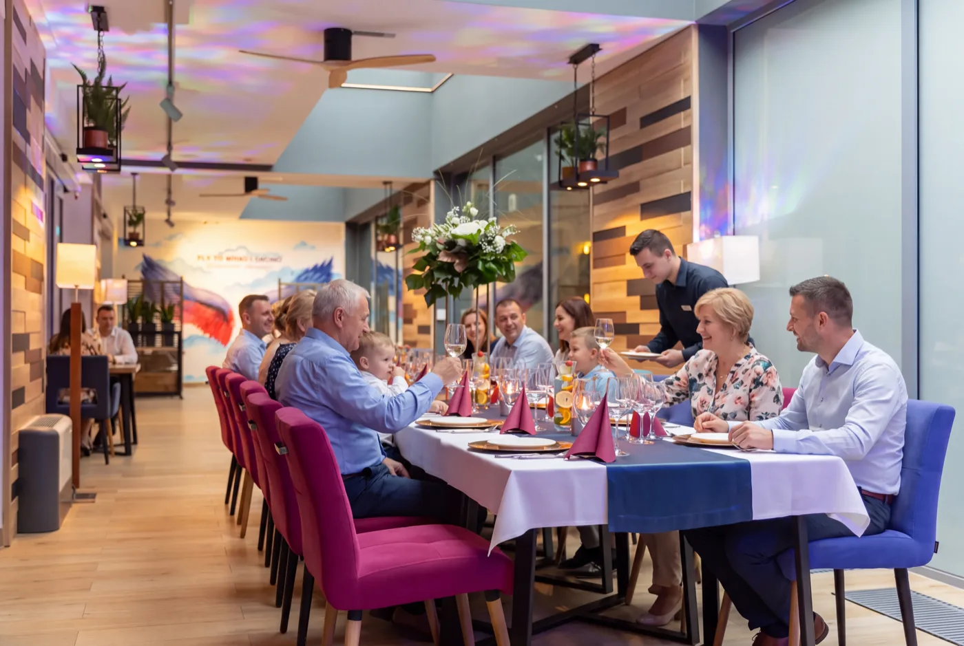 Przyjęcie rodzinne przy długim stole w sali restauracji