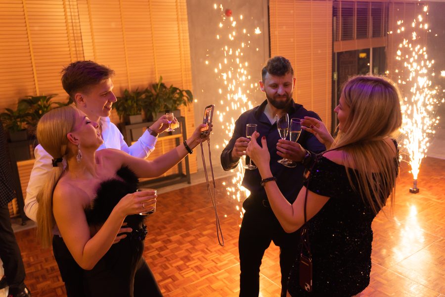 Dwie pary z kieliszkami szampana robią sobie zdjęcie przy zimnych ogniach