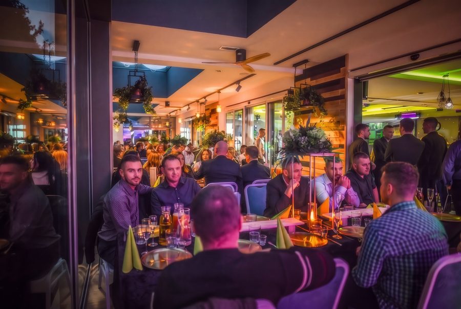 Goście przy nakrytych stołach w restauracji, wieczór w ciepłym świetle