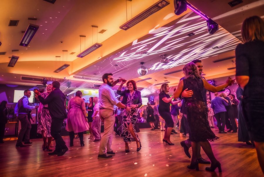 Goście tańczą na zatłoczonym parkiecie pod kulą disco