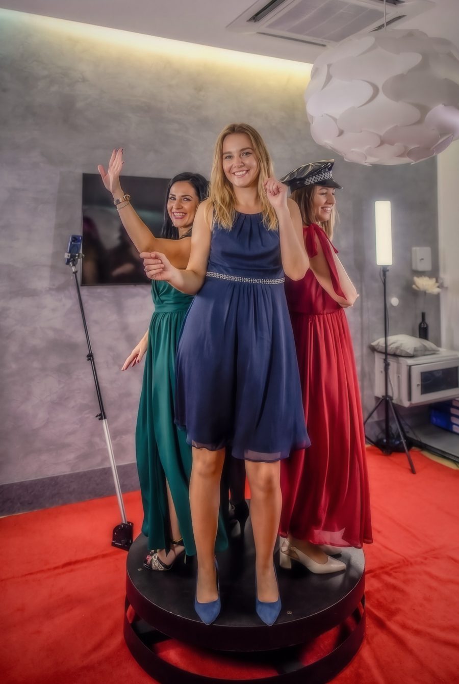 Trzy kobiety w sukniach na platformie fotobudki 360 na czerwonym dywanie